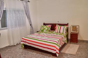a bedroom with a bed with a striped blanket at J&B Home in Kribi