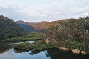 Calabash Bay Lodge في Berowra: نهر في وسط وادي به اشجار