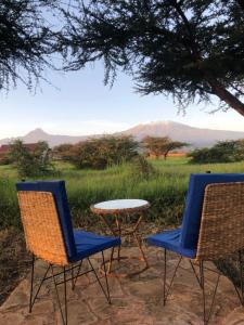 dos sillas y una mesa frente a un campo en Amboseli Cultural Camping en Amboseli