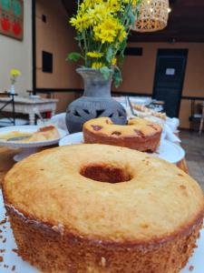 una mesa cubierta con pasteles y un jarrón con flores en Kastel Itaipava en Itaipava