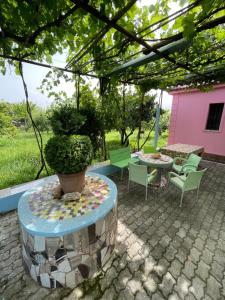 un patio con mesa, sillas y una maceta en Villa Mance, en Berat