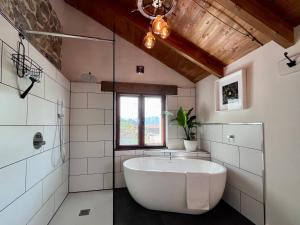 a bathroom with a large tub and a window at Casa con vistas a la montaña, cerca a la costa entre Arriondas y Ribadesella in Cangas de Onís +34 photos