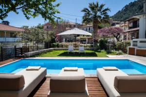 a pool with two lounge chairs and an umbrella at AV Suites - Giorgio in Kariá