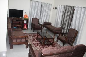 a living room with a couch and chairs and a television at COORG WINDYSIDE HOMESTAY With Campfire PAID in Madikeri
