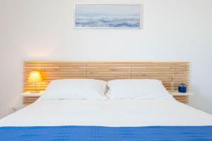 a bedroom with a white bed with a wooden headboard at Villa Medea in Casarano