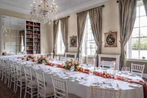 un lungo tavolo con tavoli e sedie bianchi in una stanza di Buxted Park Country House a Buxted