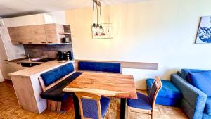 cocina con mesa de madera y sillas azules en Apartments Bergblick, en Sonnenalpe Nassfeld