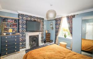 a bedroom with a bed and a tv and a fireplace at Marwood Cottage in Ripon