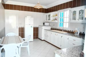 een keuken met witte apparatuur en een tafel en stoelen bij 3 bedrooms house at Djerba Midoun 800 m away from the beach with terrace and wifi in Taguermess