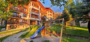 un parque infantil frente a un edificio con tobogán en Apartmanica Double room apartment with balcony, St Ivan Rilski 4 star SPA Resort, Bansko en Bansko