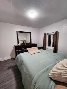 a bedroom with a bed with a dresser and a mirror at Oasis de la Baie in Port-Daniel
