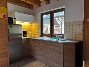 Una cocina con refrigerador de acero inoxidable y ventana. en Kameleon Dźwirzyno, en Dźwirzyno