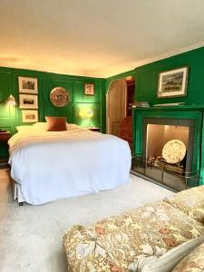 a green bedroom with a bed and a fireplace at Clarendon Cottage in Enfield