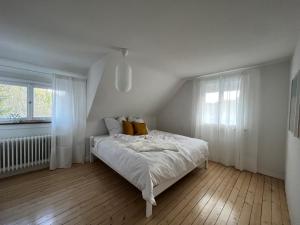 a white bedroom with a bed and a window at HAUS AM SEE - Natur Pur in Friedenweiler