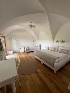 a white bedroom with a bed and a table at Penzion Kaplanka in Znojmo