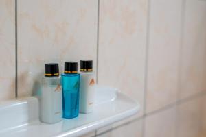 three bottles ofodorizers sitting on a shelf in a bathroom at A'lure Hotel & Residences in Kampala