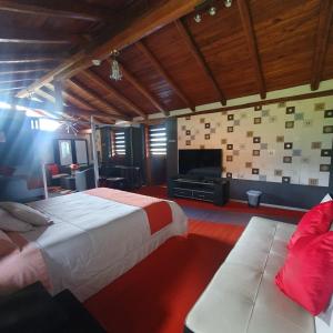 a bedroom with a bed and a couch and a television at Hosteria Airport Garden in Tababela