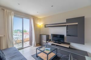 a living room with a flat screen tv and a couch at Vue mer, 2 pièces Terrasse, 5 min du centre in Antibes