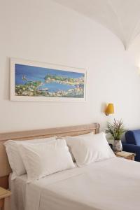 a bed with white sheets and a picture on the wall at Hotel Terme Oriente - Beach & SPA in Ischia +103 photos