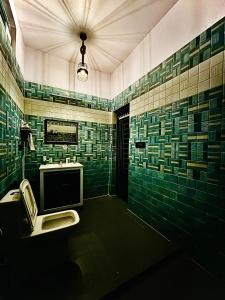 een groene betegelde badkamer met een toilet en een wastafel bij Gaonvasi Homestay in Uttarkāshi