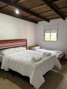 a bedroom with two beds with white sheets and a window at Posada TyM in Trinidad