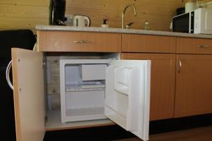 Camping pod Lyts Dekema 1 في Baard: وجود ثلاجة مفتوحة في مطبخ مع حوض