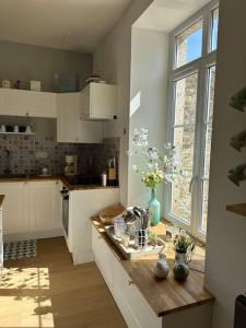 a kitchen with white cabinets and a counter with flowers on it at Gite 'la fée de Montigny sur Aube' in Montigny-sur-Aube