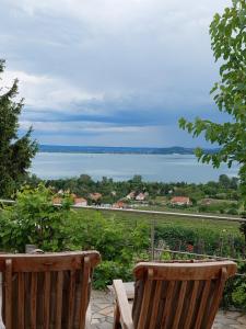 a balcony with two chairs and a view of the water at Maison Bagatell Badacsony in Badacsonytomaj