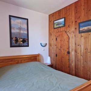 1 dormitorio con 1 cama y pared de madera en Le Dy en fleurs en Saint-Maurice-en-Cotentin