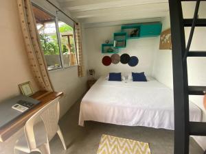 Habitación pequeña con cama blanca y escritorio. en A Piece of Paradise en San Carlos