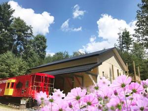 ClydeにあるSeaboard Coast Line 0843 sleep in a caboose on a bison ranchのピンクの花が咲いた建物の隣に停まっている赤い電車