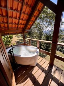 eine Badewanne auf einer Veranda mit einem Fenster in der Unterkunft Reserva Santo Antônio in Santo Antônio do Pinhal