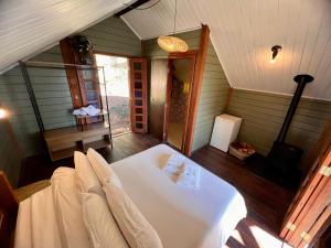 um quarto com uma cama branca num sótão em Reserva Santo Antônio em Santo Antônio do Pinhal