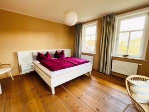 1 dormitorio con cama blanca y almohadas rojas en Altes Pfarrhaus Neustädt en Neustädt