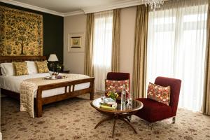 a bedroom with a bed and a table and chairs at Fernhill House Hotel & Gardens in Clonakilty
