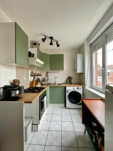 a kitchen with green cabinets and a tile floor at 35m2 à la Madeleine: Salon, Cuisine & sdb privés in La Madeleine