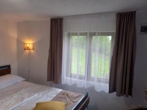 a bedroom with a bed and a large window at Casa rustica Cerdacul Batranesc in Urlueşti