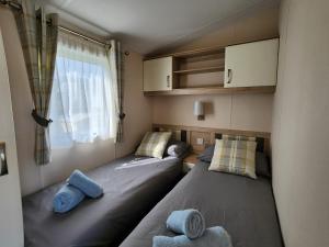 two beds in a small room with a window at Europa Willow Pitch 29 Creek Caravan Park dog friendly in Ringstead