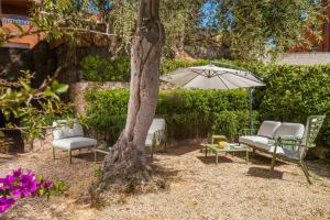 un patio con sillas y una sombrilla junto a un árbol en 0.8 Guest House, en Porto Ercole
