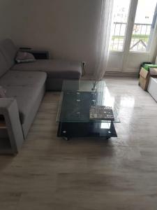 a living room with a couch and a glass coffee table at Chambre Neuve dans un logement partagé in Allonnes