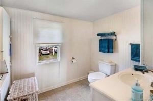 een badkamer met een wastafel, een toilet en een raam bij Cozy Beach - Direct Waterfront! in East Haven