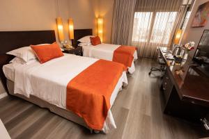 Habitación de hotel con 2 camas con sábanas de color naranja en Libertador Hotel en Buenos Aires