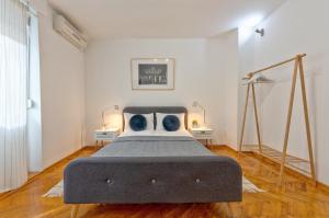 a bed in a white room with two tables at ZigZag Belgrade in Belgrade