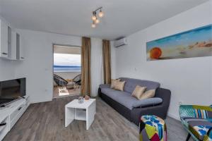 a living room with a blue couch and a tv at Villa Legero mit Pool 300 Meter zum Strand in Drašnice