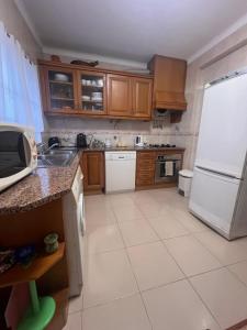 eine Küche mit Holzschränken und einem weißen Kühlschrank in der Unterkunft Escape House in Almograve + 4 Fotos