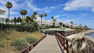 a boardwalk leading to a beach with palm trees and buildings at Miraflores Beach & Country Club in Mijas Costa
