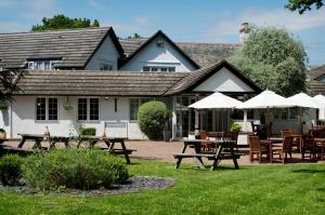 a restaurant with tables and umbrellas in front of a building at Basingstoke Country Hotel & Spa in Hook