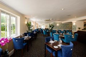 um restaurante com cadeiras e mesas azuis numa sala em Basingstoke Country Hotel & Spa em Hook