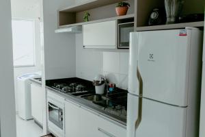 uma cozinha branca com um fogão e um frigorífico em Residencial Diva em Florianópolis
