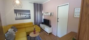 a living room with a yellow couch and a television at Apartments Podkoren 82 in Kranjska Gora